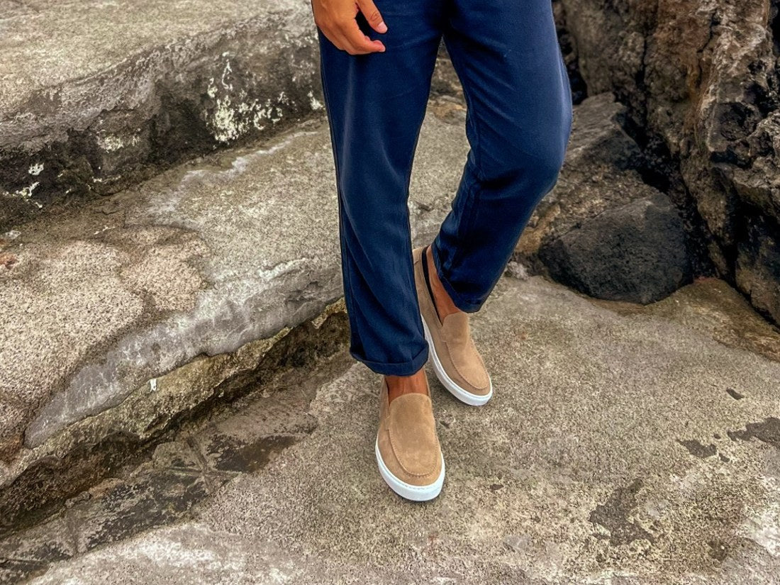 A Rossano client wearing suede loafers on coastal stone steps